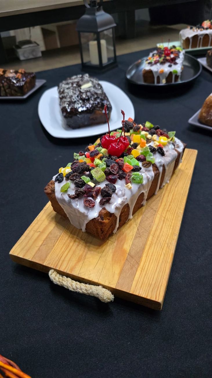 Panqué artesanal glaseado con frutas cristalizadas y cerezas sobre tabla de madera