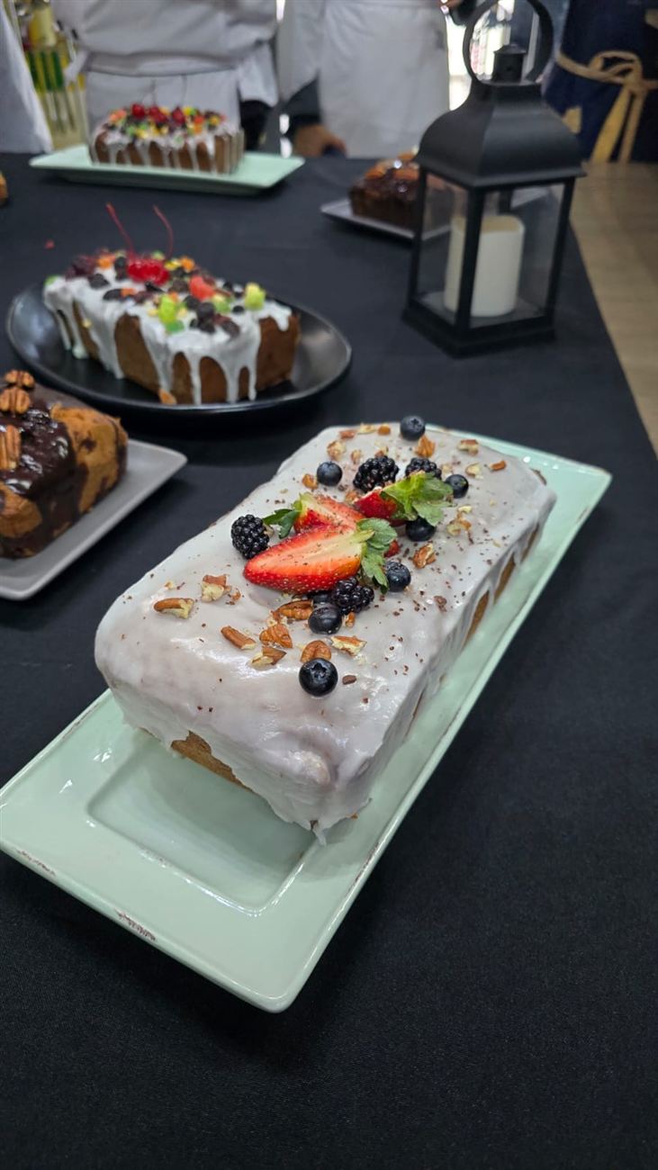 Panqué glaseado coronado con fresas, moras, arándanos y nuez sobre plato verde menta