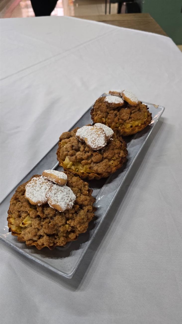 Tres tartaletas de manzana con crumble de canela y galletitas espolvoreadas con azúcar glass